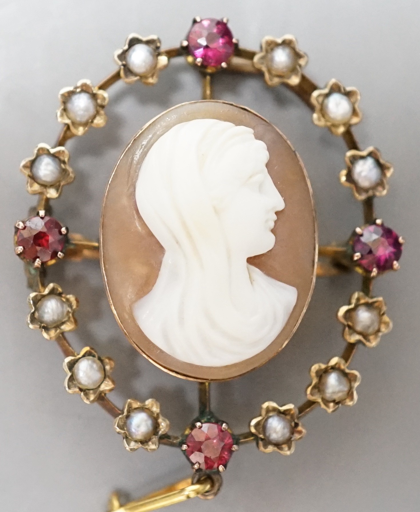 An Edwardian yellow metal, split pearl and ruby mounted oval cameo shell pendant brooch, 32mm, gross weight 6 grams.
